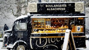 Francuski food truck w śniegu. Czarna furgonetka piekarnia